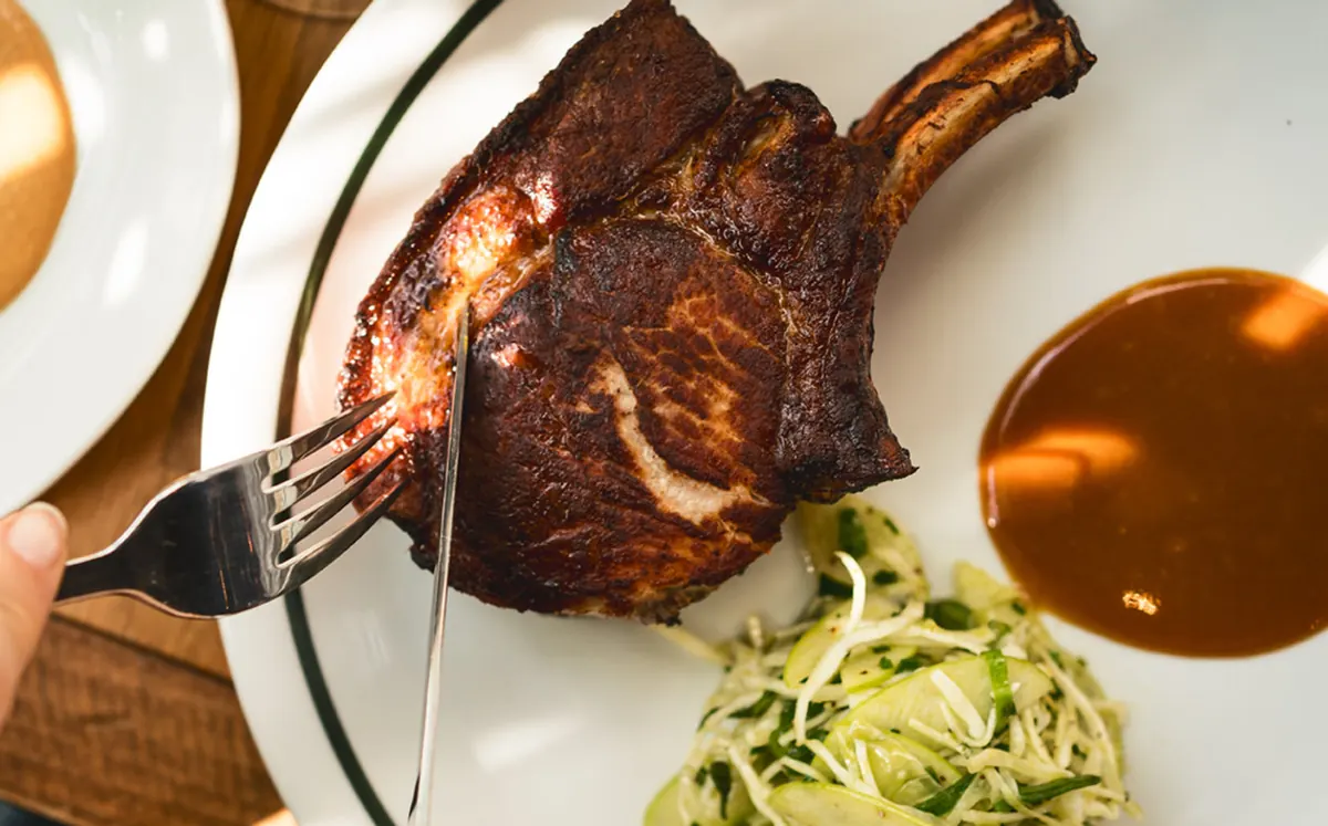 Charcoal-grilled pork chop with sauce and slaw