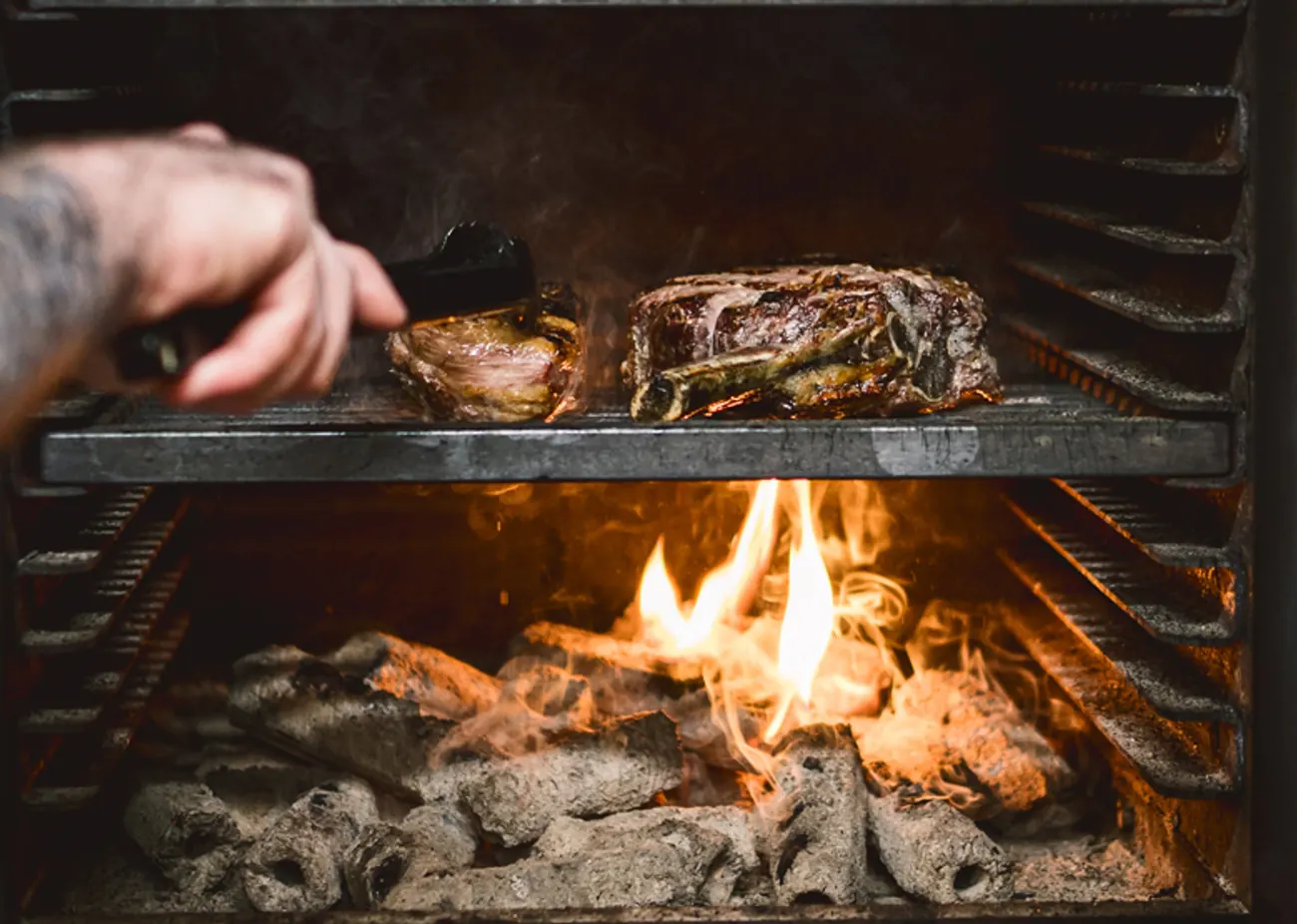 Steaks cooking over the charcoal grill at NORA'S