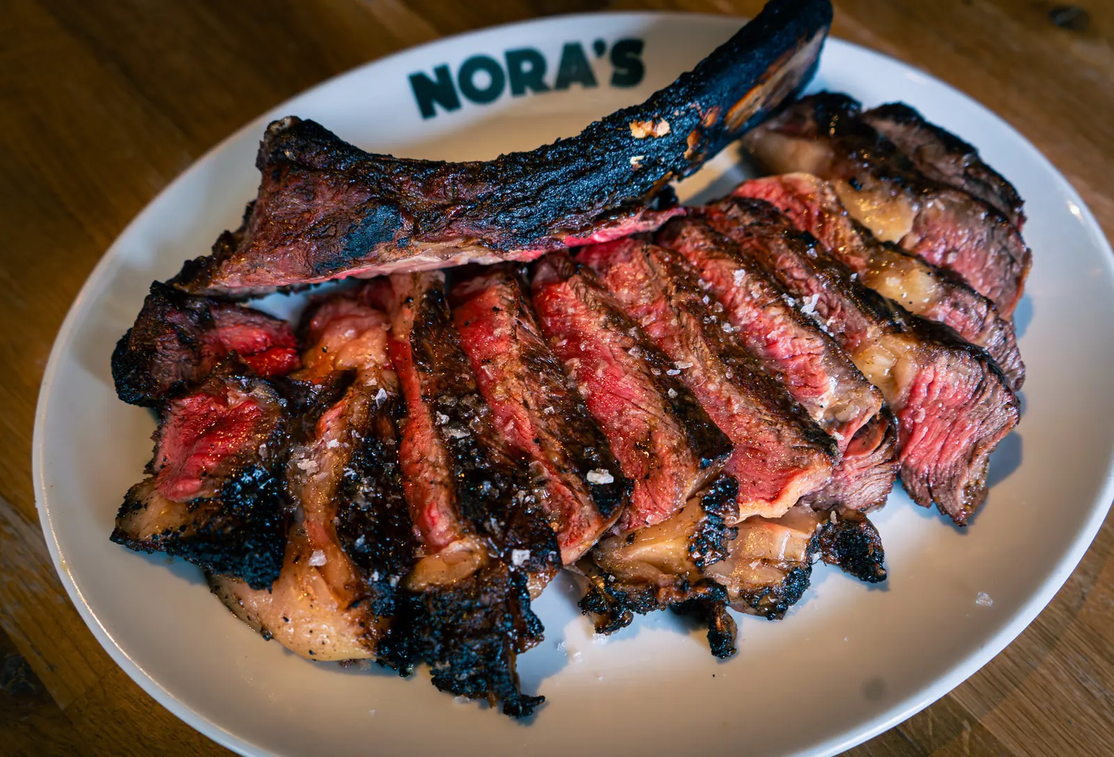 Sliced bone-in steak on a NORA'S plate